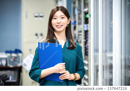 一位面帶微笑的日本女工作人員在電視台控制室裡拿著一個資料夾。 20 拍攝合作:Sky Perfect TV 東京媒體中心 一位面帶微笑的日本女工作人員在電視台控制室裡拿著一個資料夾。 20 拍攝合作:Sky Perfect TV 東京媒體中心 137047228