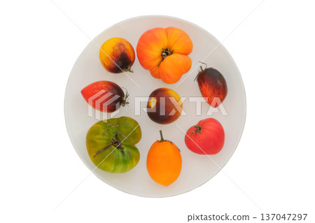 Variety tomatoes on a ceramic plate isolate on white background. Red tomato in white plate. Food marketing. Top view. Variety tomatoes on a ceramic plate isolate on white background. Red tomato in white plate. Food marketing. Top view. 137047297