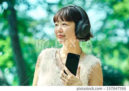 Young woman wearing wireless headphones outdoors Young woman wearing wireless headphones outdoors 137047566
