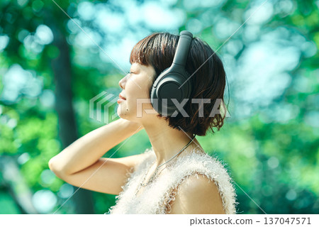 Young woman wearing wireless headphones outdoors 137047571