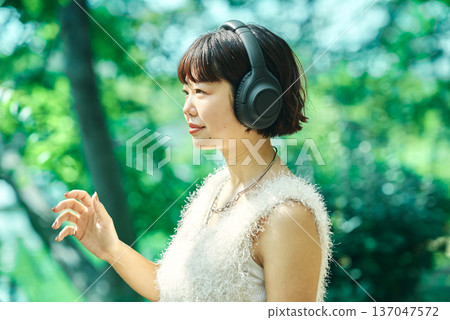 Young woman wearing wireless headphones outdoors 137047572