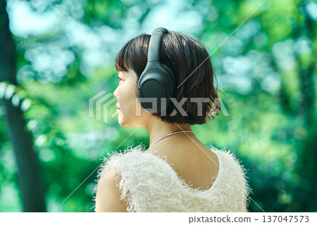 Young woman wearing wireless headphones outdoors 137047573