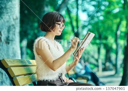 年輕女子在戶外使用平板電腦 年輕女子在戶外使用平板電腦 137047901