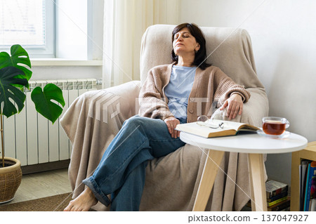 Woman resting comfortably at home with tea and book 137047927