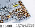 Professional tap and die set with titanium coating for thread cutting in a gray storage case. 137048335