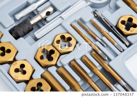 Close-up of a titanium-coated tap and die set for threading in a plastic organizer case. 137048337