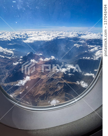 Mountains and clouds from an airplane window 137048494