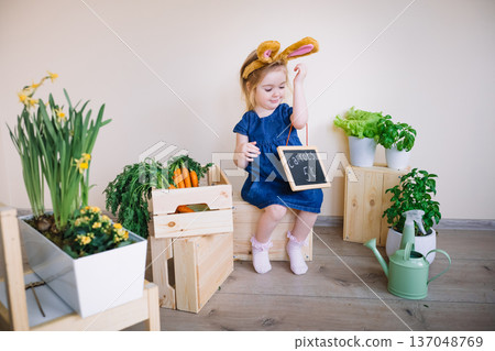 Cute little child girl wearing bunny ears on Easter day. Funny 3 years old girl holding price board Cute little child girl wearing bunny ears on Easter day. Funny 3 years old girl holding price board 137048769