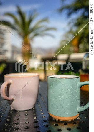 Pink and Green Coffee Mugs with Latte on Outdoor Terrace Pink and Green Coffee Mugs with Latte on Outdoor Terrace 137048978
