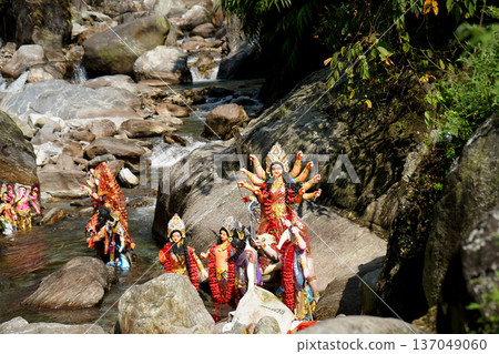 Goddess Durga and other deities immersed in a rocky mountain river during a traditional ritual 137049060