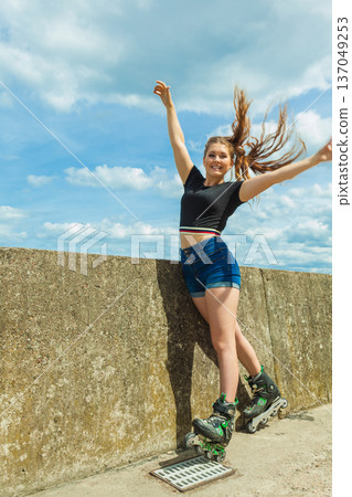 Happy young woman wearing roller skates Happy young woman wearing roller skates 137049253