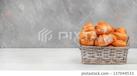 Golden croissants in wicker basket on light table with copy space 137049533