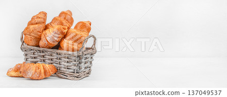 Fresh croissants in wicker basket on light background with copy space Fresh croissants in wicker basket on light background with copy space 137049537
