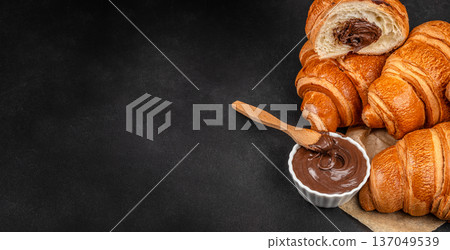 Chocolate croissants with creamy spread on dark background Chocolate croissants with creamy spread on dark background 137049539