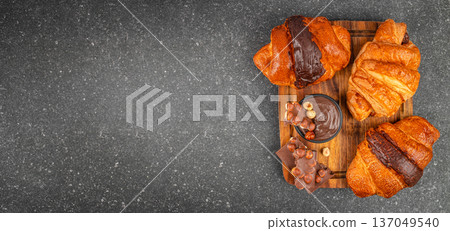 Chocolate croissants with hazelnut spread on wooden board, top view with copy space 137049540