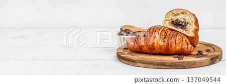 Chocolate filled croissant with spread on wooden board and copy space Chocolate filled croissant with spread on wooden board and copy space 137049544