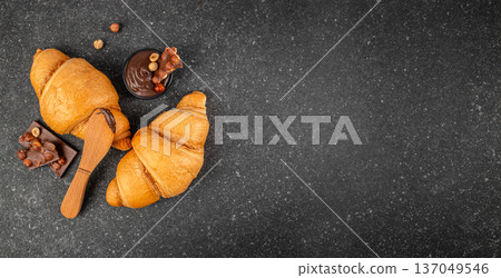 Croissants with chocolate spread and hazelnut pieces on dark background, top view with copy space 137049546