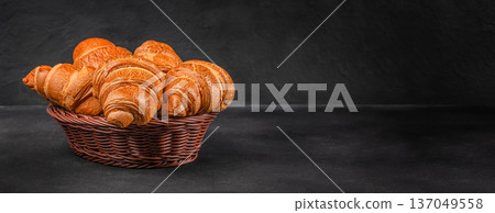 Golden croissants in wicker basket on dark rustic background Golden croissants in wicker basket on dark rustic background 137049558