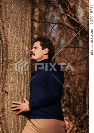 Man Embracing Tree Trunk in Sunlit Forest 137049783