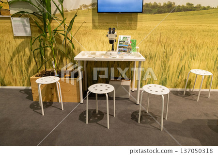 Modern white table with stools in green agricultural exhibition space Modern white table with stools in green agricultural exhibition space 137050318