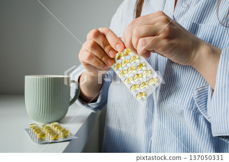 Woman taking fish oil omega 3 capsules for woman health. Supplements and vitamins, self treatment, biohacking. Woman taking fish oil omega 3 capsules for woman health. Supplements and vitamins, self treatment, biohacking. 137050331