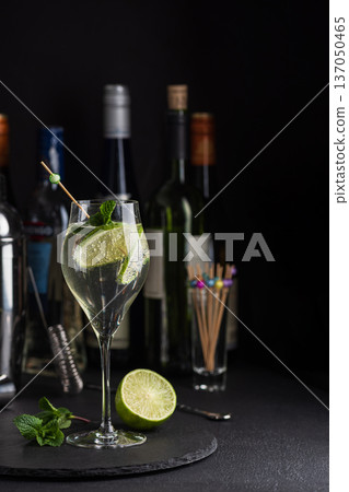 Elegant cocktail Martini Royale garnished with lime slices and fresh mint leaves against a refined bar background with cocktail tools 137050465