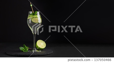 Elegant cocktail Martini Royale garnished with lime slices and fresh mint leaves on dark background 137050466