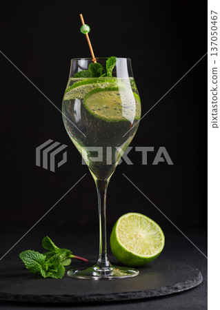 Elegant cocktail Martini Royale garnished with lime slices and fresh mint leaves on dark background 137050467