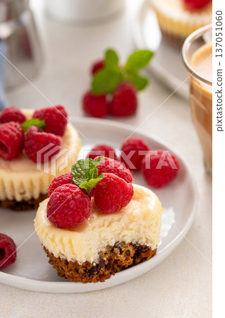 Mini cheesecakes topped with fresh raspberries on a serving plate 137051060
