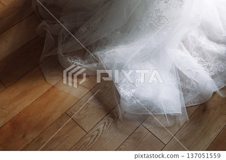White lace wedding dress tulle lying on polished wooden parquet floor White lace wedding dress tulle lying on polished wooden parquet floor 137051559