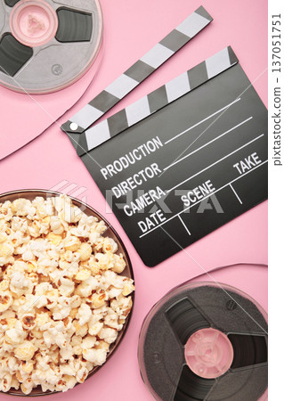 Movie clapper with popcorn and film reels on pink background 137051751
