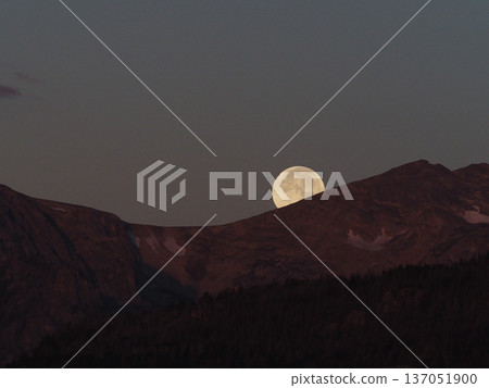 A full moon setting over the mountains on a quiet morning A full moon setting over the mountains on a quiet morning 137051900