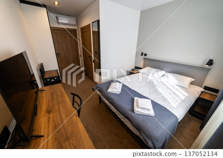 Modern minimalist hotel bedroom interior with double bed workspace and natural daylight Modern minimalist hotel bedroom interior with double bed workspace and natural daylight 137052134