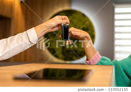Receptionist giving hotel room key to guest during check in at modern reception desk 137052135