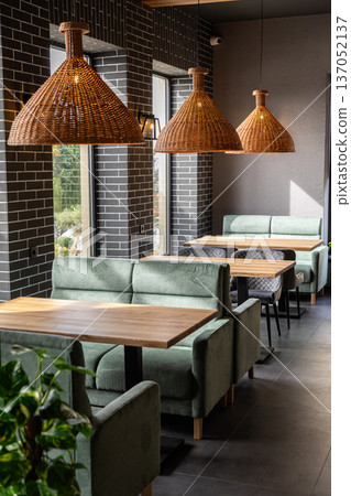 Stylish modern restaurant interior with cozy seating and natural light from large windows Stylish modern restaurant interior with cozy seating and natural light from large windows 137052137