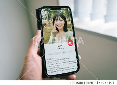 Image of a man looking at a woman's profile on a matching app 137052493