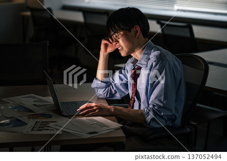 A young businessman working overtime until late at night 137052494