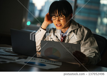 A young businessman who works overtime until late at night without finishing his work 137052496