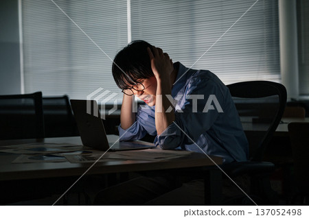 一位年輕的商人經常加班到深夜，卻仍無法完成工作。 137052498