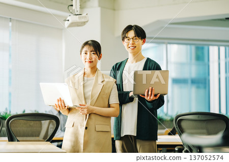 Young IT engineer man and woman with laptop Young IT engineer man and woman with laptop 137052574