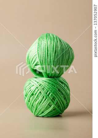 A ball of green recycled polyester synthetic fabric on beige background. Green living, plastic recycling, reuse 137052907