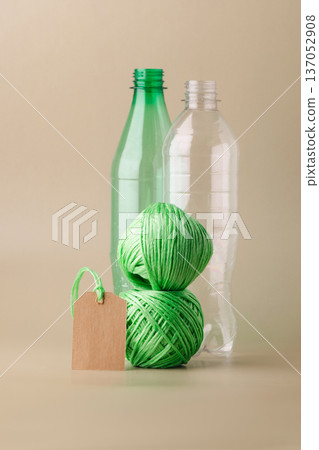 Empty plastic bottles, several skeins of polyester thread, blank label promoting recycling, sustainability, eco-friendly production. Green lifestyle, eco-technologies 137052908