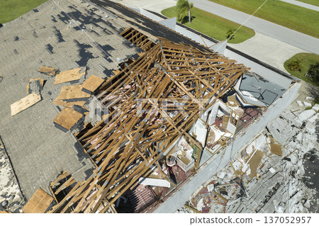 Consequences of natural disaster. Damaged house roof with missing shingles and broken apart walls after hurricane Ian in Florida 137052957
