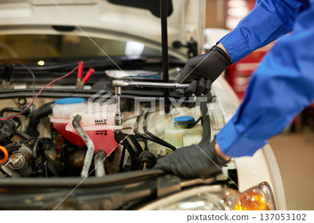 汽車修理工正在引擎蓋下修理。 汽車修理工正在引擎蓋下修理。 137053102