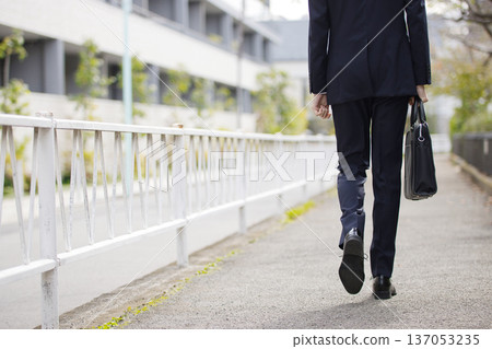 A businessman in his twenties walking outdoors A businessman in his twenties walking outdoors 137053235