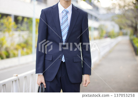 A businessman in his twenties walking outdoors A businessman in his twenties walking outdoors 137053258