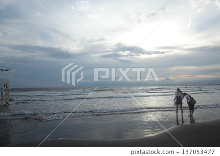 Two people looking at the sea at dusk 137053477