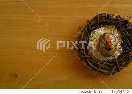 Photo with copy space of traditional straw Easter eggs in a bird's nest on a wooden table 137054210