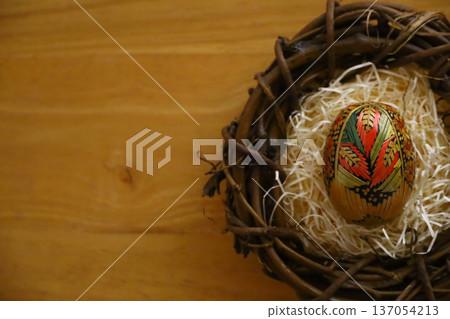 Photo with copy space of traditional straw Easter eggs in a bird's nest on a wooden table 137054213