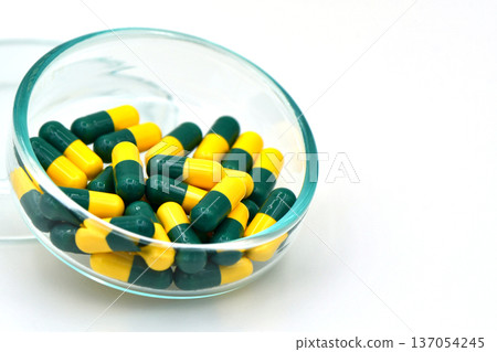Green and Yellow Tramadol Capsule Pills in Glass Bowl on White Background with copy space. 137054245